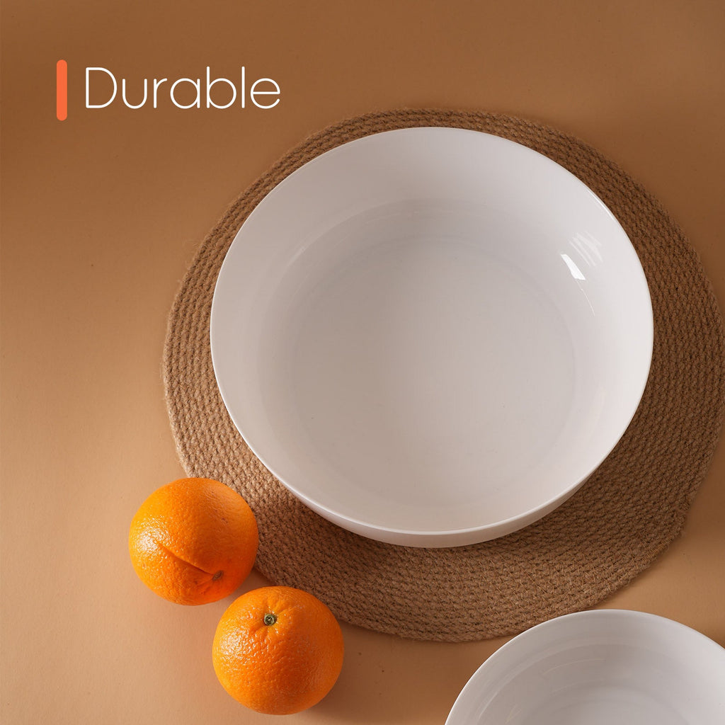 A set of white opal glass bowls arranged on a woven brown placemat against a warm beige background, with two oranges beside the largest bowl and the word 'Durable' in the top left corner.